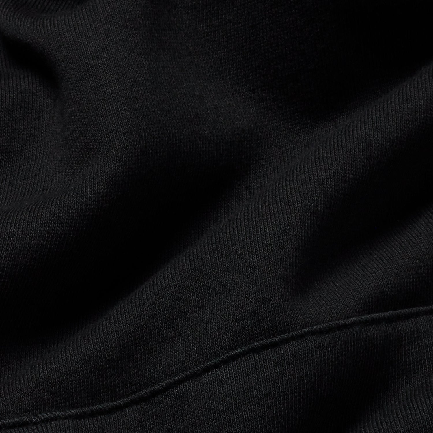 Close-up of black hoodie's fabric showing fine texture detail.