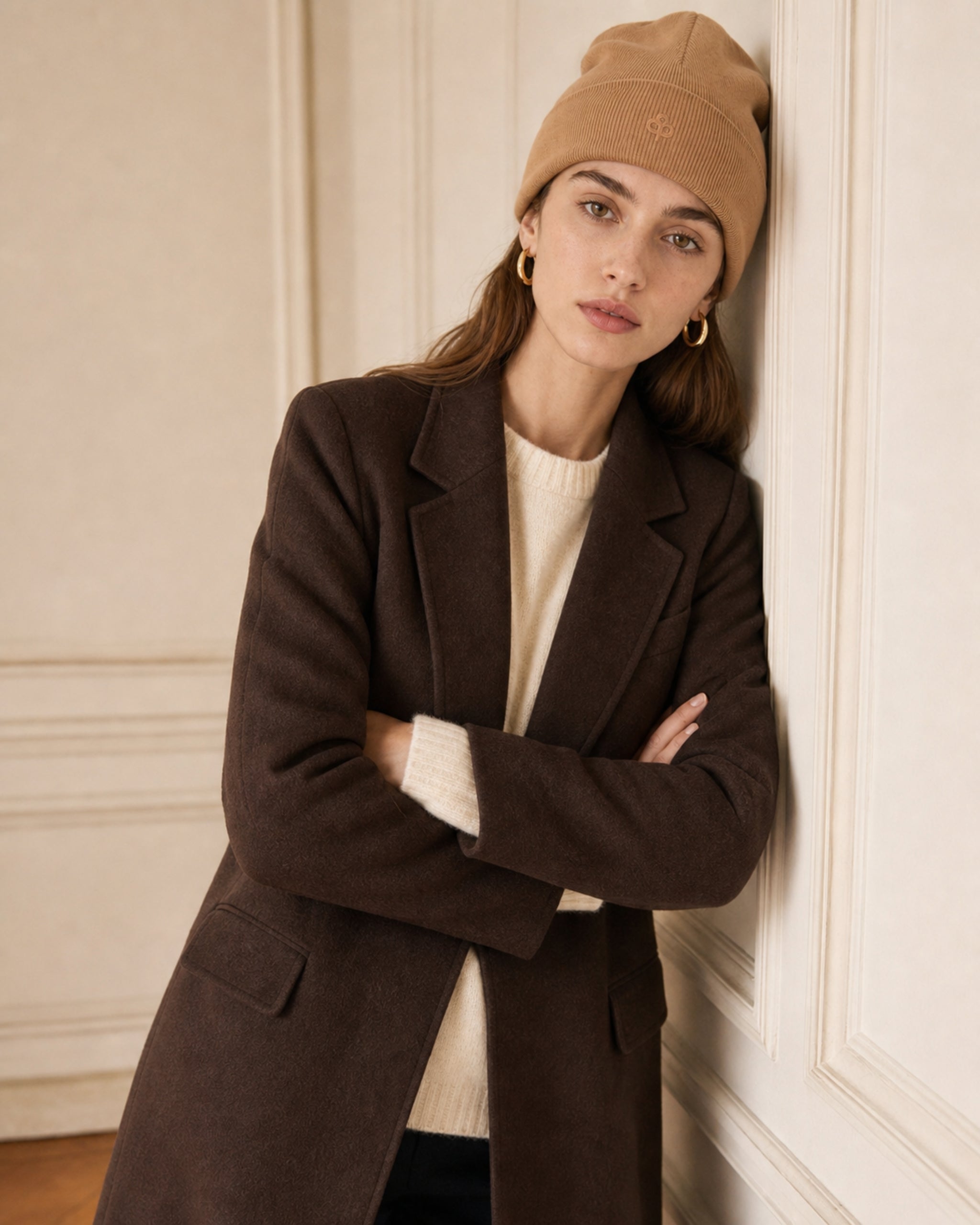 Frau mit Rippstrick-Beanie in Camel und brown wool coat, verschränkte Arme