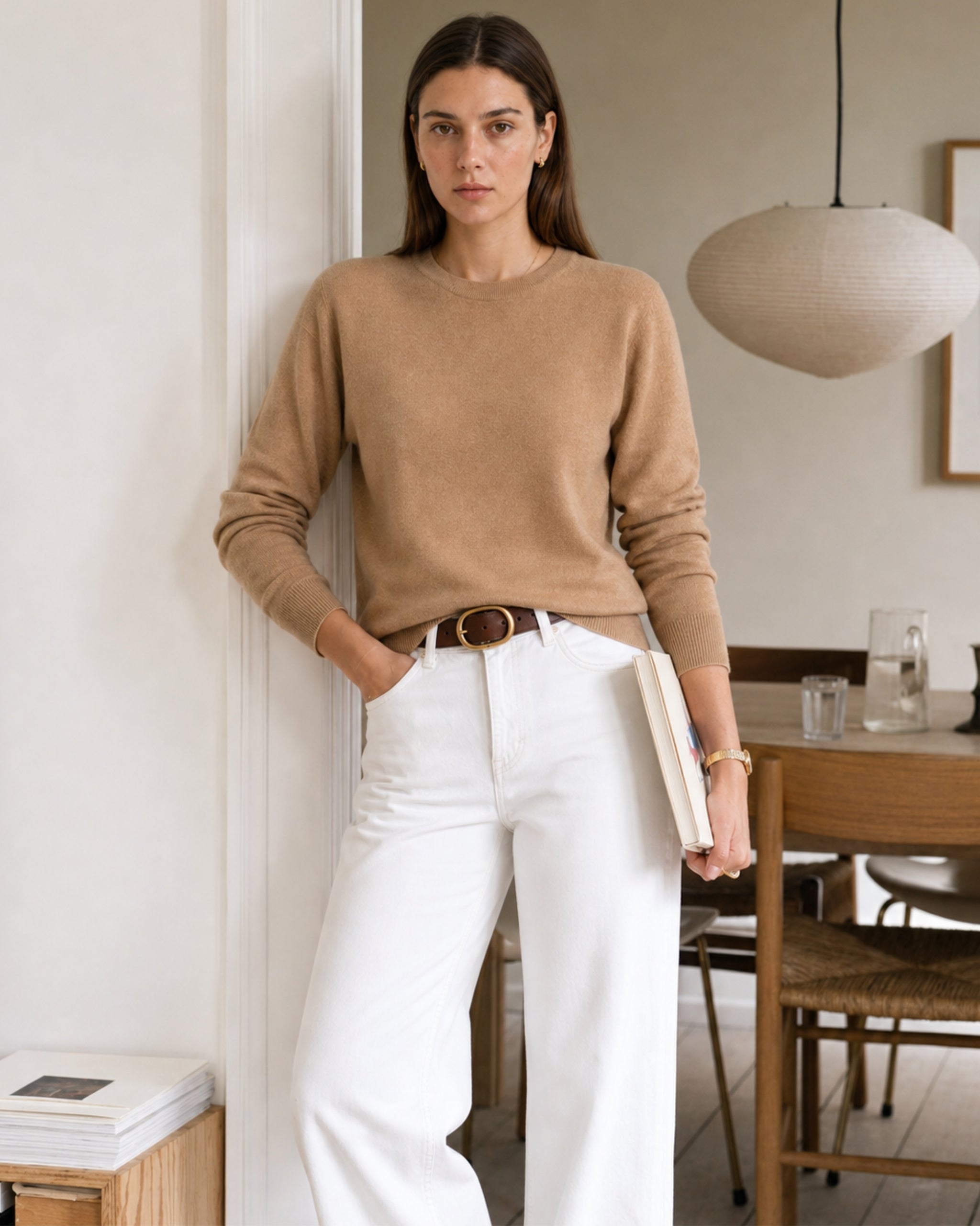 Frau mit Merino-Pullover in Camel und white jeans mit Buch in der Hand home