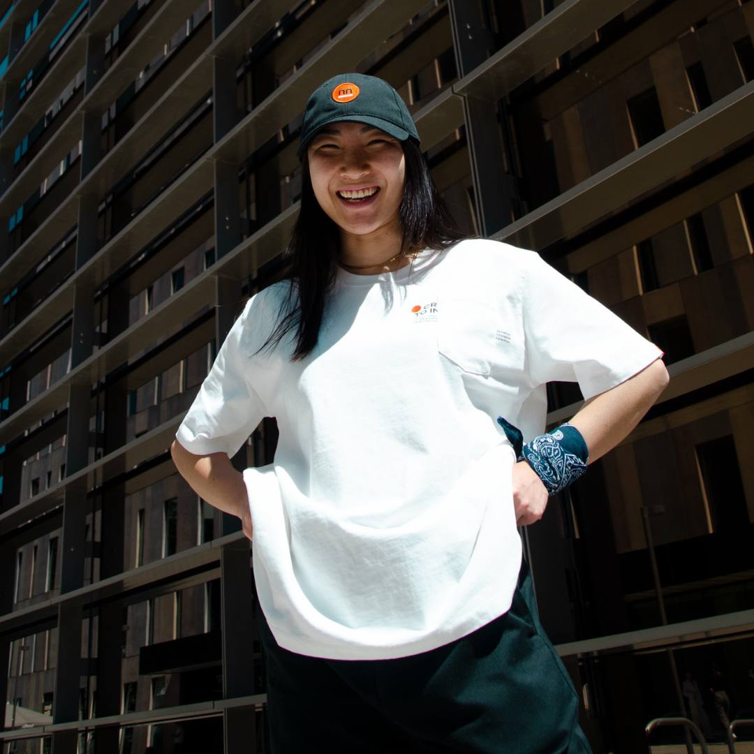 Women wearing white t-shirt and navy cap with a modern building background.